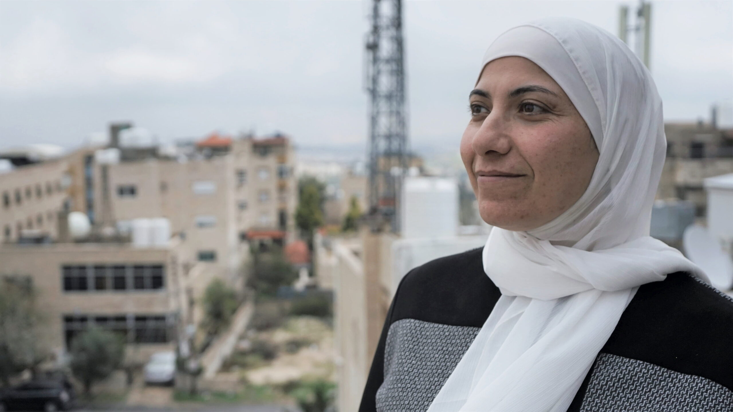 Areej Samreen In front of blurred buildings and sky in Jordan