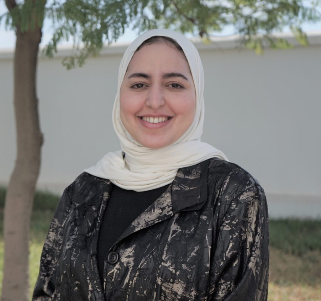 Asmae standing outside under a tree