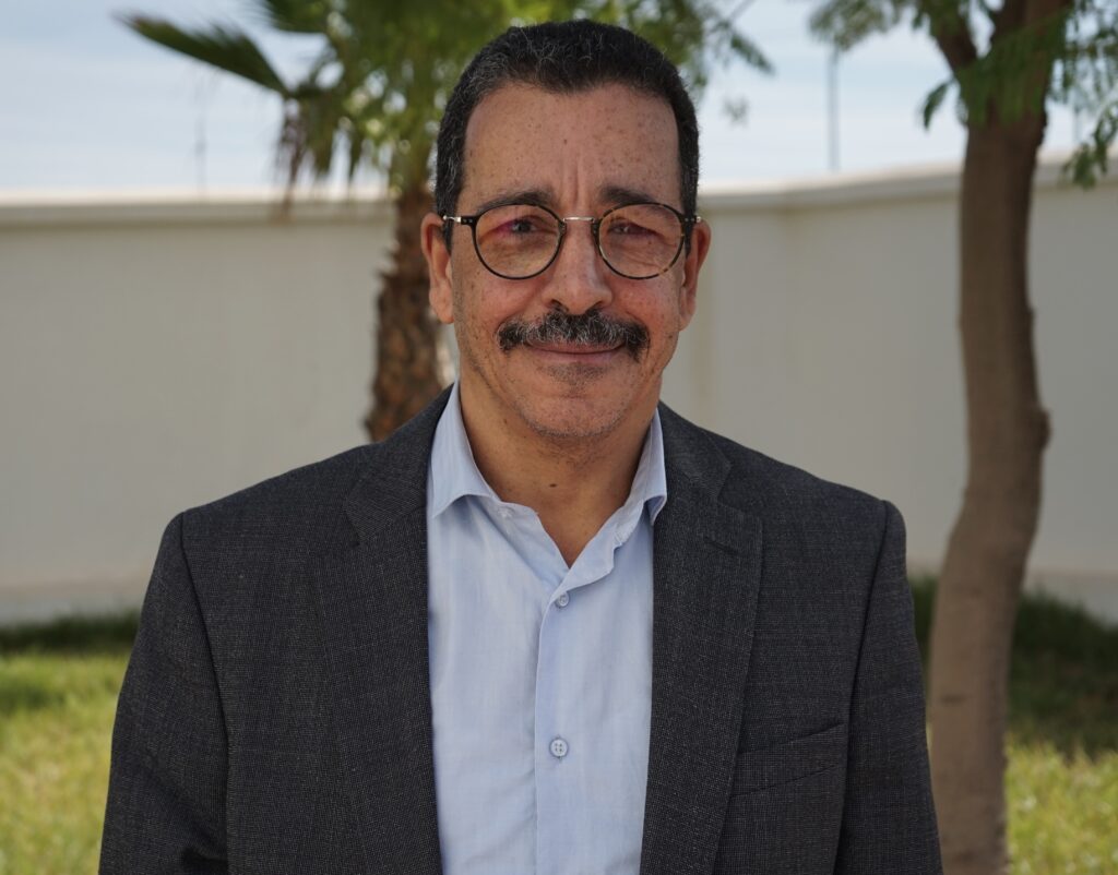 Azelarabe Lahkim Bennani standing outside in front of two palm trees