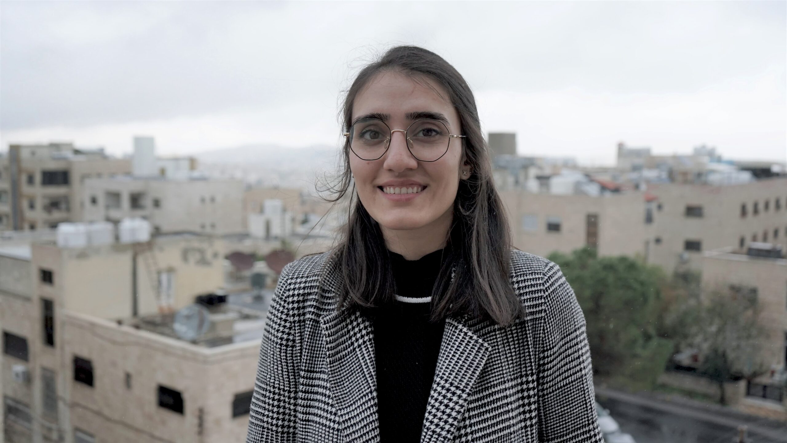 Fathia Zorba In front of blurred buildings and sky in Jordan