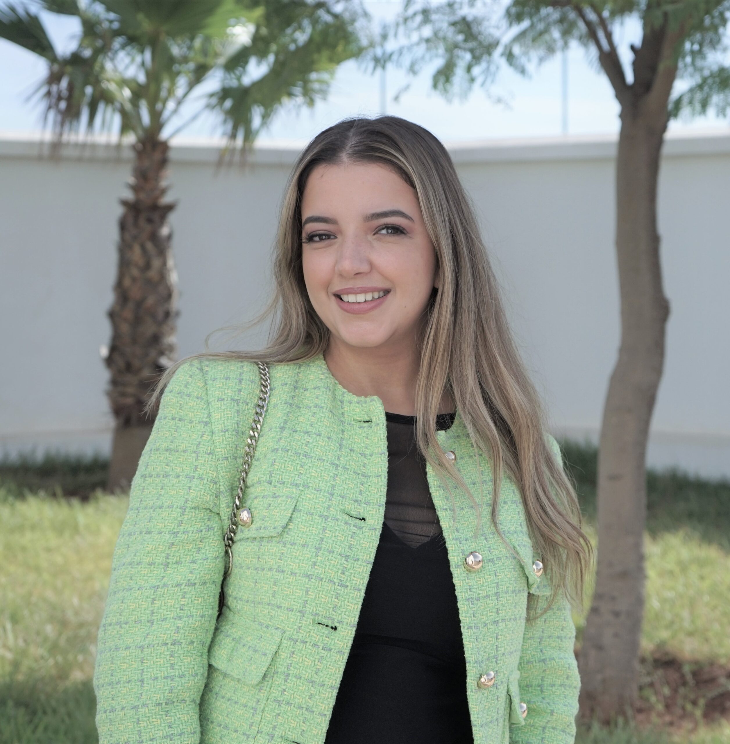 Hiba standing outside in front of two palm trees