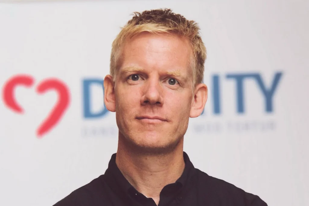 Rasmus, DIGNITY's direktør der står foran et dignity skilt