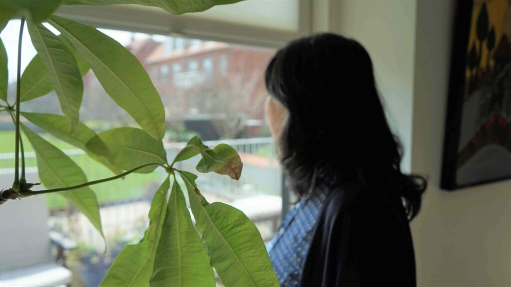 Teresa står skråt bagfra og kigger ud af vinduet